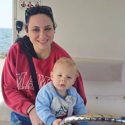 Woman and baby steering a boat on a sunny day.