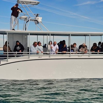 People on a modern white boat on a calm sea under a clear sky.