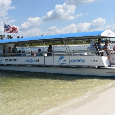 A boat with passengers on a sandy shore under a blue sky with clouds.