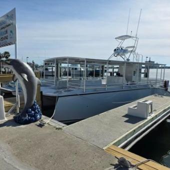 Docked boat with dolphin statue in foreground on a sunny day.