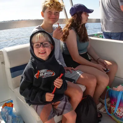 Three people sitting on a boat; two smiling, one looking away.