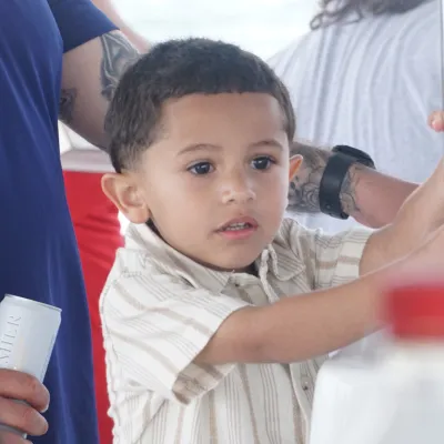Small child holding a pole, surrounded by adults in casual clothing.