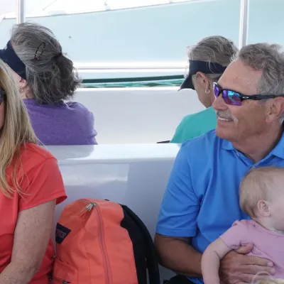 Two adults sitting on a boat, one holding a baby.