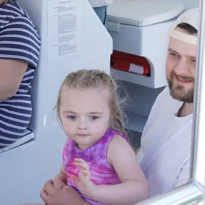 Child and adults sitting on a boat, smiling.