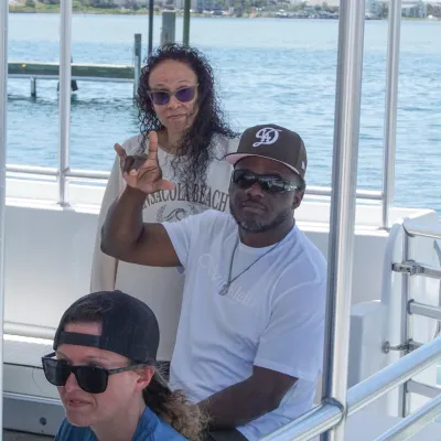 Three people sitting on a boat near the water.