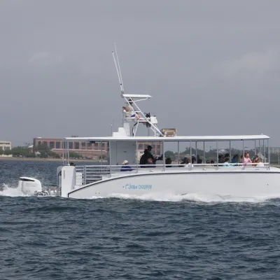 White boat with people on board sailing on a cloudy day.