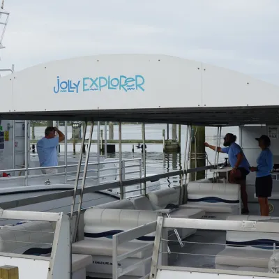 Tour boat 'Jolly Explorer' docked with flag and people on board.