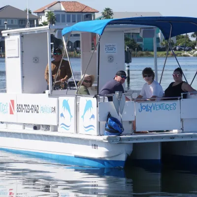 Small boat with six passengers, including a captain, on calm water near houses.