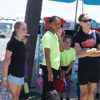Group of children standing outdoors near beach gear.