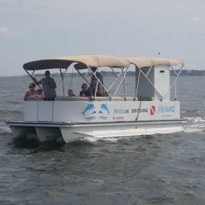 Small tour boat with canopy on calm water, people aboard enjoying scenery.